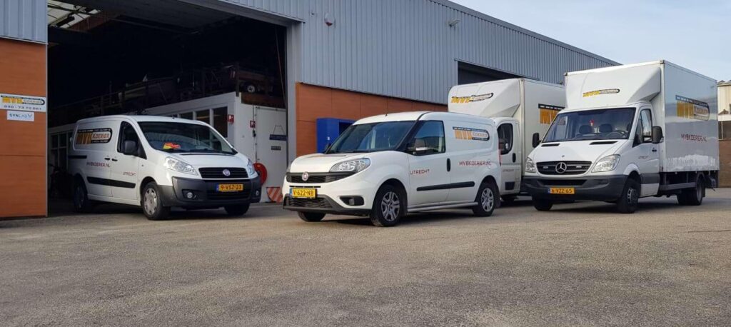Bestelbussen en een bakwagen van MVB Koerier voor een loods